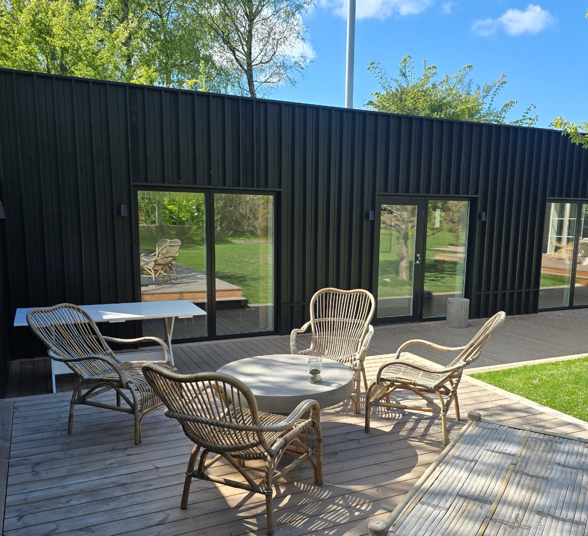 AplusH — terrasse med rotting møbler og sort trækledning